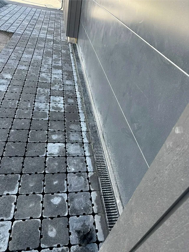 Dreneringsrenne langs vegg med belegningsstein.